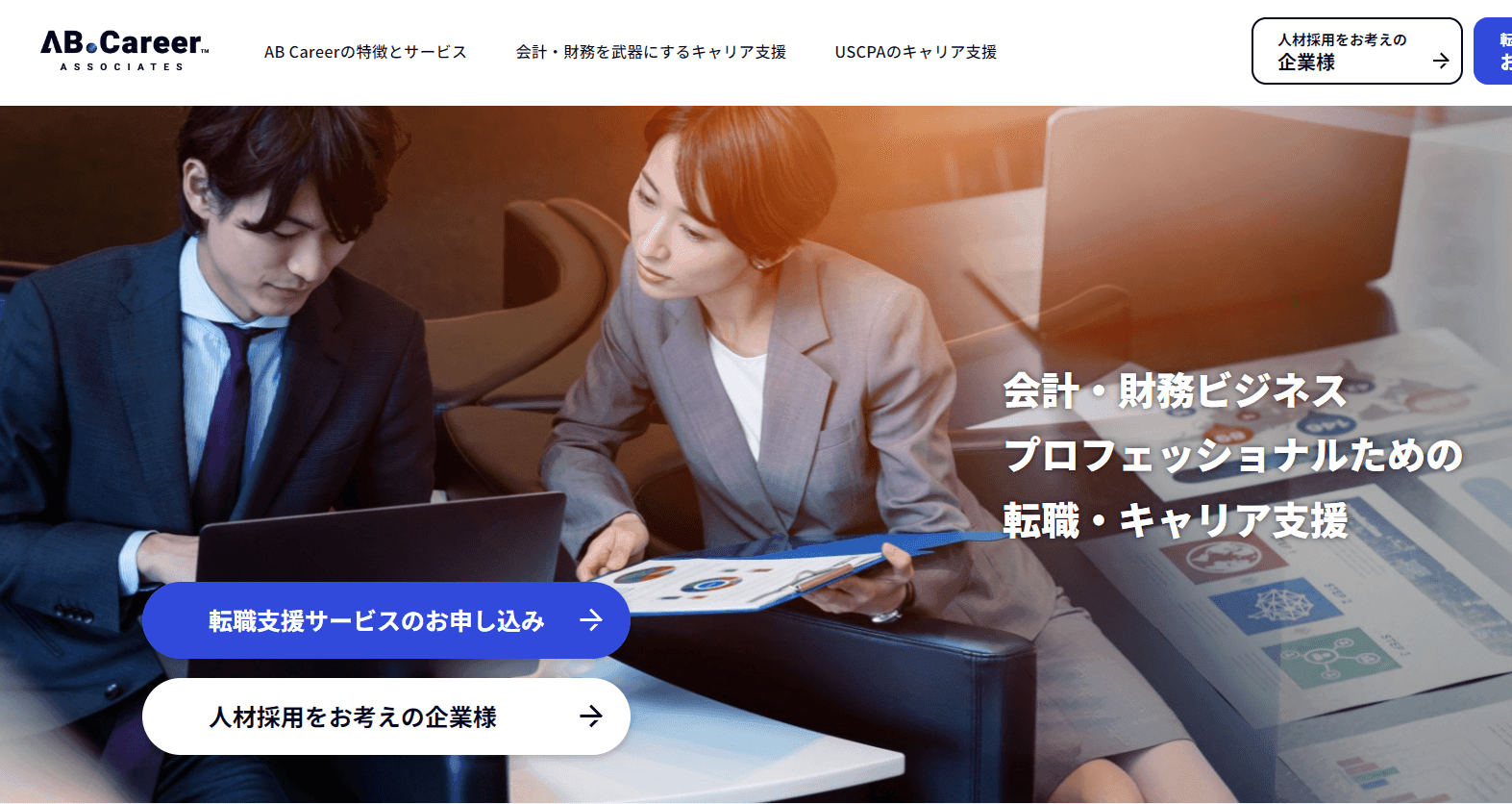 Two professionals in formal attire discussing business documents and working on a laptop in an office setting.